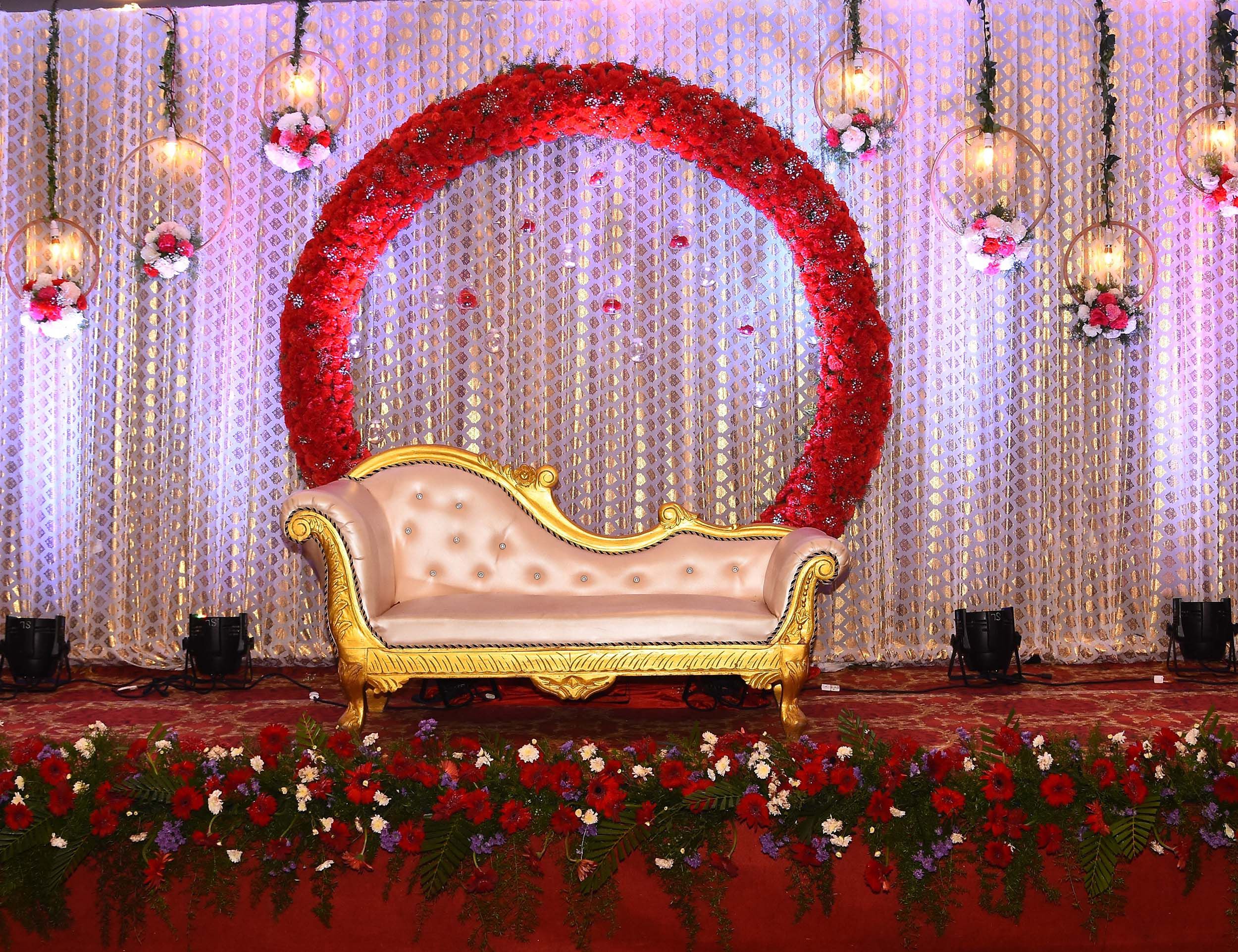Beautifull red theme wedding reception stage with red flowers around.